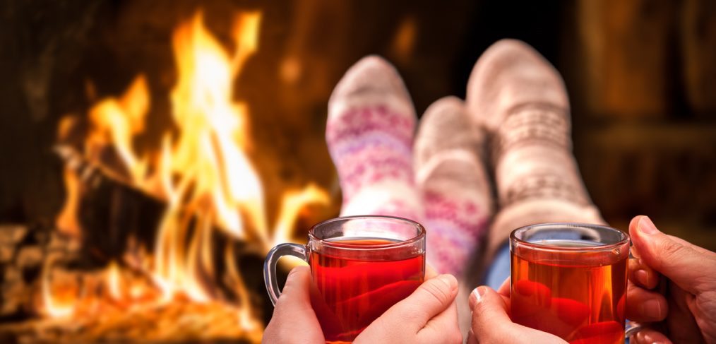 Drinks. A couple having a cozy cup of tea by the fire.